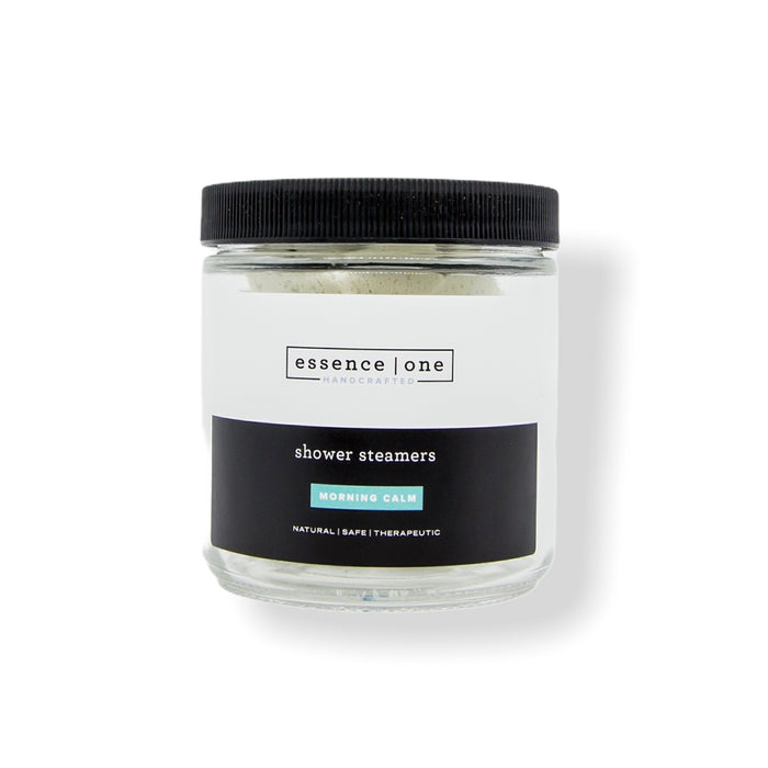 Glass jar with black lid containing shower steamers branded as Shower Steamer | Essence One, promoting natural, safe, and therapeutic body care for a calming wellness experience.