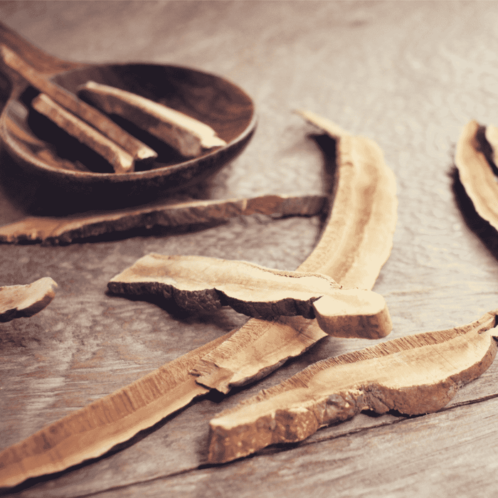 Close-up of dried natural root herbal slices on a wooden surface, suggesting ingredients for skincare and wellness, related to Skin Brightening Serum | Privai.
