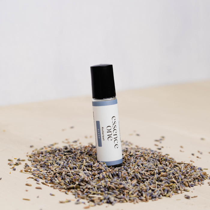 Sleep Rollerball - Sleep Support | Essence One bottle placed upright on a light wooden surface surrounded by dried lavender buds, promoting natural wellness and relaxation.