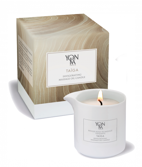 White ceramic massage candle burning next to its textured beige box packaging labeled Taiga Massage Candle | Yon-Ka Paris for skincare and body care wellness.