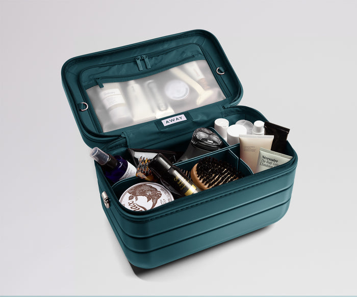 Open teal makeup bag with various cosmetic items on a light gray background