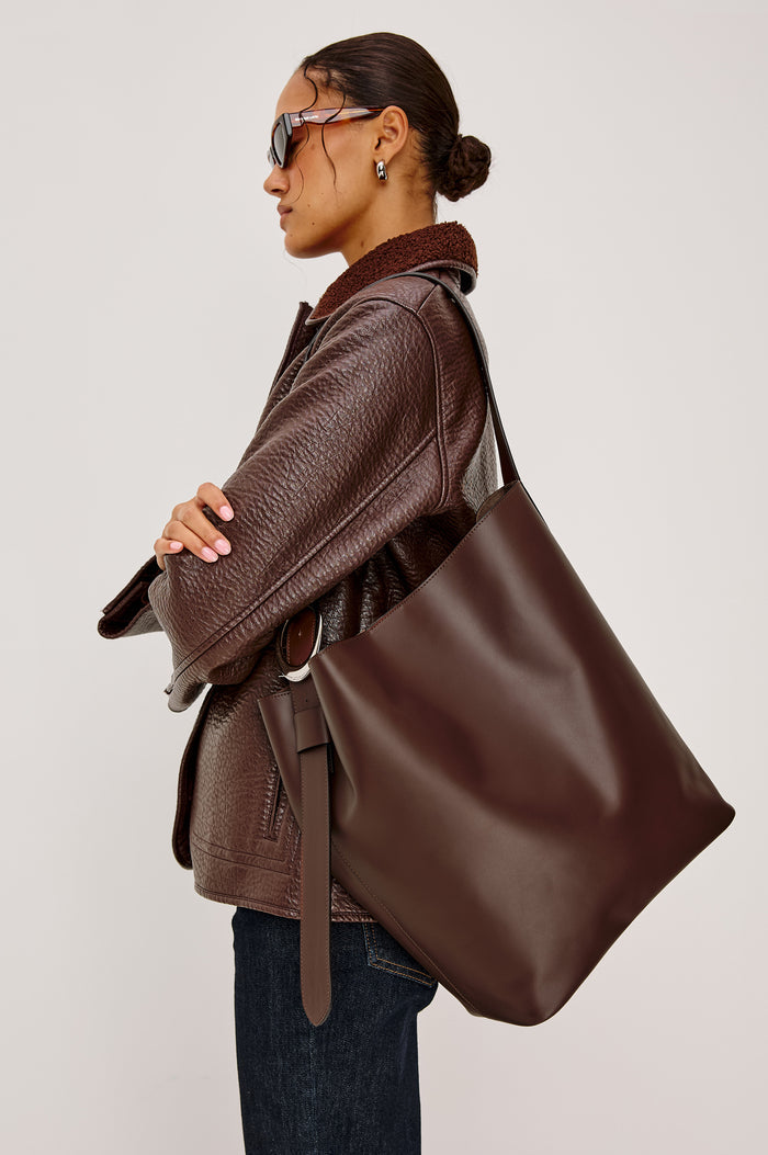 Torino Bucket Bag in Italian Leather With Adjustable Strap and Polished Silver Oval Buckle, Microsuede Lining, Interior Magnetic Closure, Snap Button-Slip Pocket, and Subtle Branded Detailing in Cowgirl Haircalf Colorway Colorway - Side View Featured