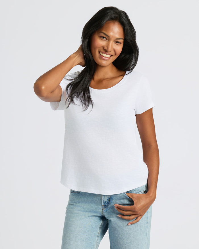 Woman wearing a white t-shirt and blue jeans on a plain background